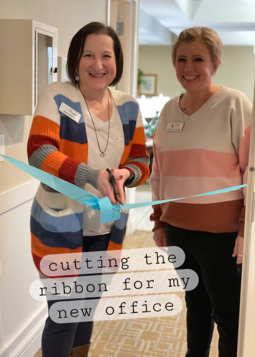 Two team members enthusiastically cutting a ceremonial ribbon to mark the opening of a new office space, reflecting their pride and achievement.