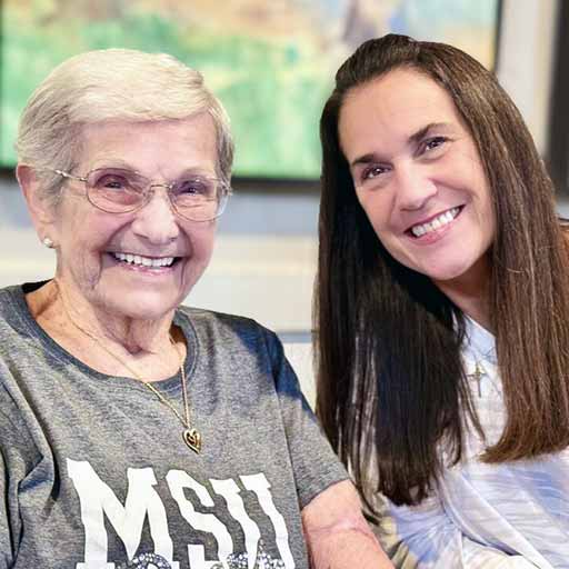 A team member and senior woman at The Township Senior Living smile joyfully together.