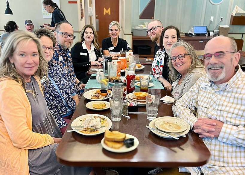 Residents and team members smile during a meal at a local restaurant.