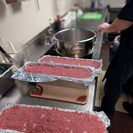 Culinary team member at The Township Senior Living prepares a large batch of meatloaf made with fresh ingredients.