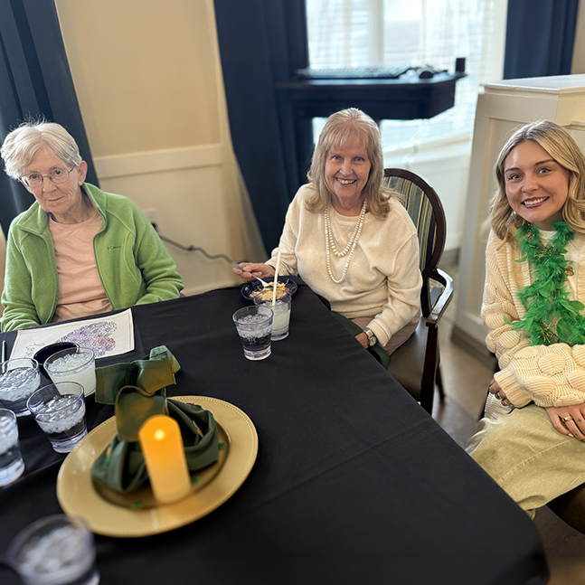 A senior woman enjoys time with family members at an elegantly set dining table at The Township Senior Living.
