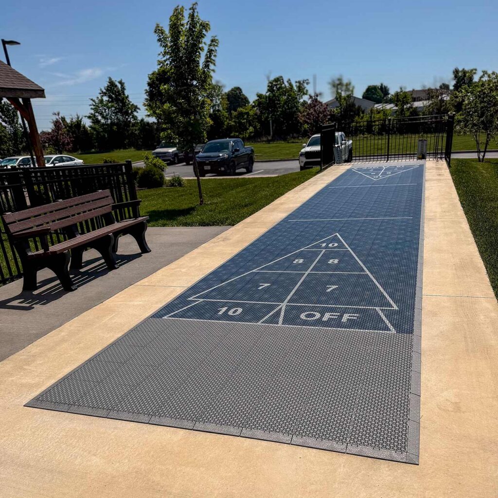 A shuffleboard court flanked with trees and a seating area at The Township.